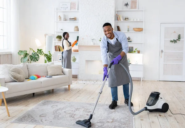 Yerleri süpüren zenci bir adam, kız arkadaşı oturma odasını temizlemesine yardım ediyor, boş bir yer. — Stok fotoğraf
