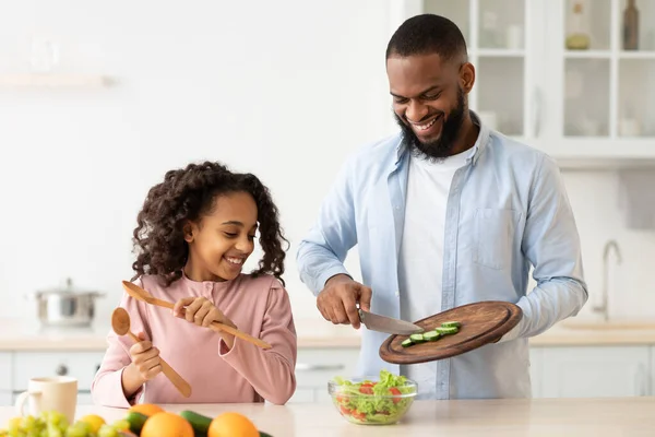 Neşeli Afrikalı Amerikalı baba ve kızı birlikte salata pişiriyorlar. — Stok fotoğraf