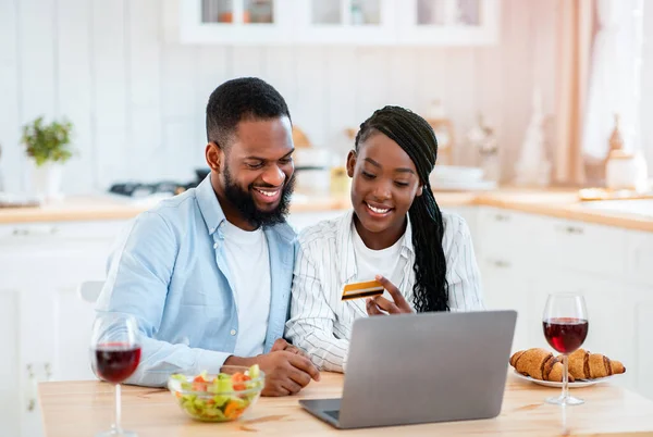 Couple noir faisant des achats en ligne avec ordinateur portable et carte de crédit dans la cuisine — Photo