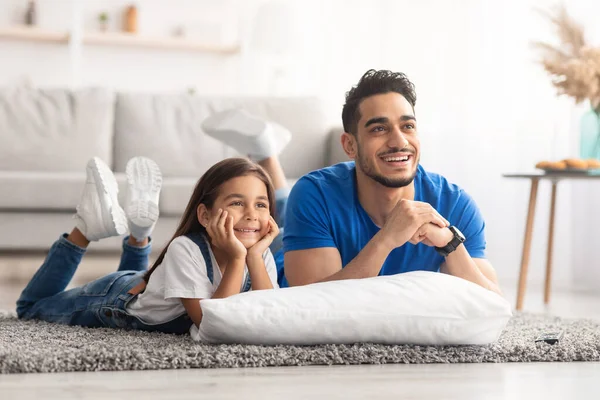 Feliz jovem família assistindo televisão deitada no chão — Fotografia de Stock