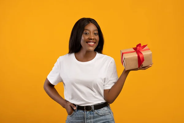 Heureuse femme afro-américaine tenant boîte cadeau sur jaune — Photo