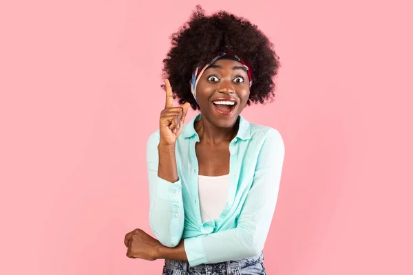 Izgatott afrikai nő ujjal felfelé, amelynek ötlete, rózsaszín háttér — Stock Fotó