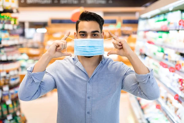 Midden-Oosterse Man toont hoe gezicht masker te dragen in de supermarkt — Stockfoto