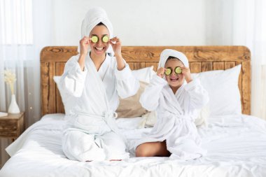 Gözlerinde salatalık çemberleri olan mutlu bir anne ve küçük kız.