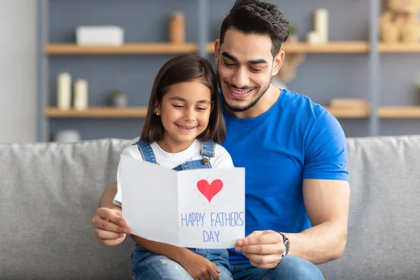 Pequena filha cumprimentando jovem smling pai com cartão — Fotografia de Stock