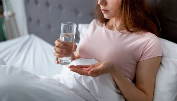 ベッドの中で睡眠薬を飲んで水のガラスを持つ若い女性の作物ビュー,コピースペース — ストック写真