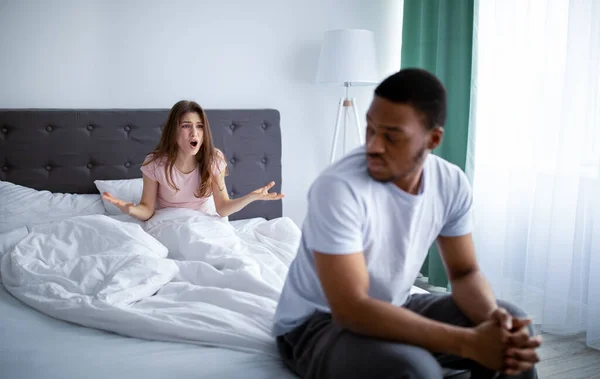 Boos jonge vrouw schreeuwen tegen haar zwarte man, conflict op bed thuis, kopieer ruimte — Stockfoto