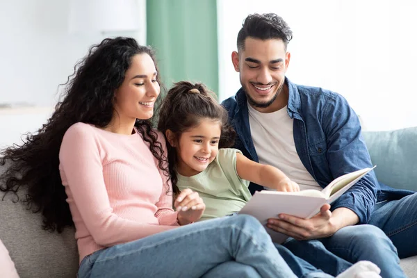 Tempo de família. Mãe árabe feliz, pai e pequena filha leitura livro juntos — Fotografia de Stock