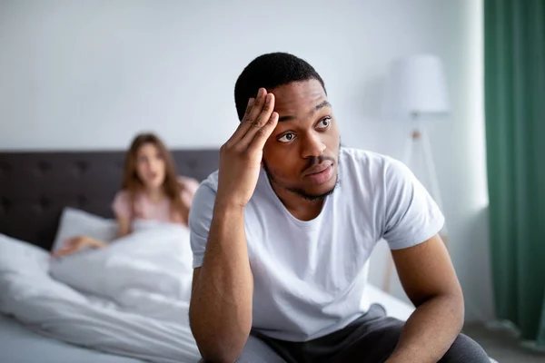 Un Afro-Américain déçu assis sur son lit, écoutant ses femmes se disputer, la tête dans le désespoir — Photo