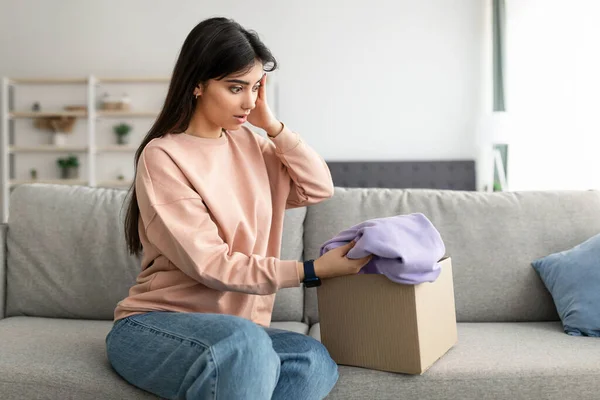 Schockierte junge Frau packt falsches Paket aus, Lieferfehler — Stockfoto