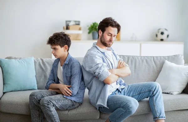 Familie conflict concept. Vader en zijn zoon zitten na ruzies rug aan rug, praten niet met elkaar. — Stockfoto