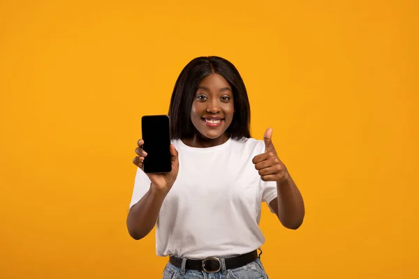 Sonriente dama negra mostrando el teléfono móvil con la pantalla vacía — Foto de Stock