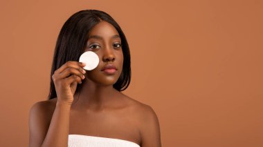 Afrikalı Amerikalı kadın duştan sonra toner ile yüzünü temizliyor.