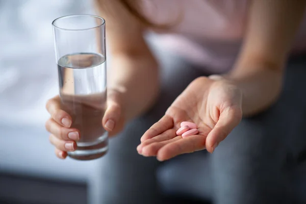 Terapia antiviral. Vista recortada de la dama milenaria con vaso de agua tomando tabletas para tratar el coronavirus en casa — Foto de Stock