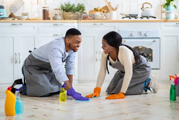 Χαρούμενο μαύρο ζευγάρι σκουπίζει το πάτωμα της κουζίνας μαζί, ολόσωμο πορτρέτο — Φωτογραφία Αρχείου