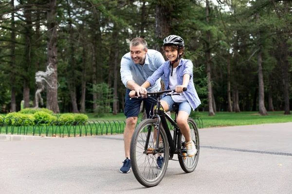 Boy learning how to ride bicycle with his happy dad — Stock Photo, Image