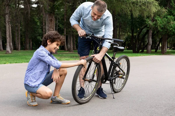 Closeup portrait of smiling dad and son checking bike — Stock Photo, Image
