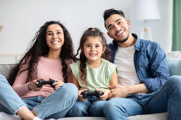 Alegre familia de Oriente Medio con la pequeña hija jugando videojuegos en casa — Foto de Stock