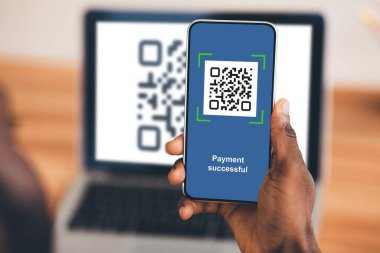 Tanımlanamayan siyah adam akıllı telefondan QR kodunu tarıyor.