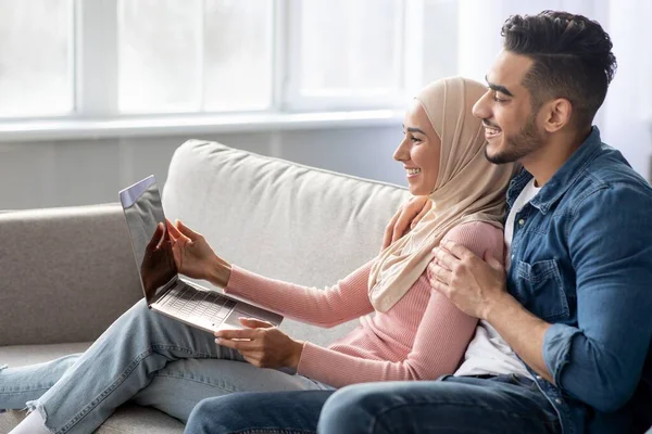Vista lateral do casal muçulmano usando laptop em casa — Fotografia de Stock