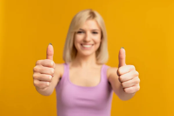 La mejor opción. Mujer sonriente mostrando los pulgares hacia arriba gesto con ambas manos, posando sobre fondo de estudio amarillo, primer plano —  Fotos de Stock