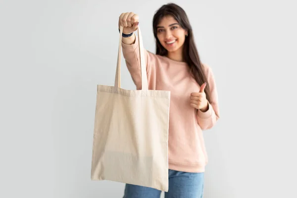 Mujer alegre de pie con bolsa de lona en blanco —  Fotos de Stock