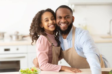 Neşeli siyah baba ve kızı mutfakta poz veriyor.