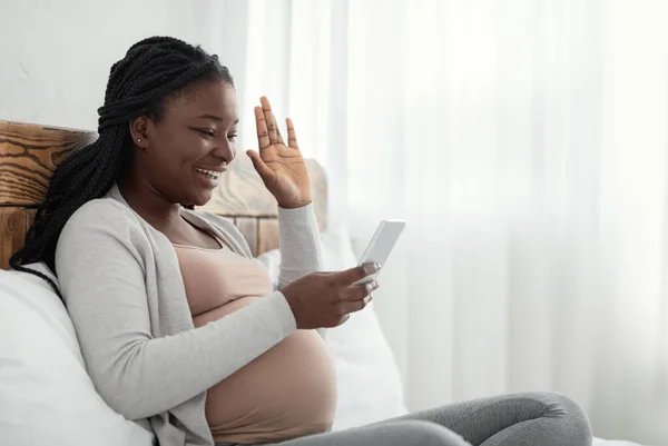 Онлайн общение. Чернокожая беременная дама звонит по видеосвязи из дома — стоковое фото