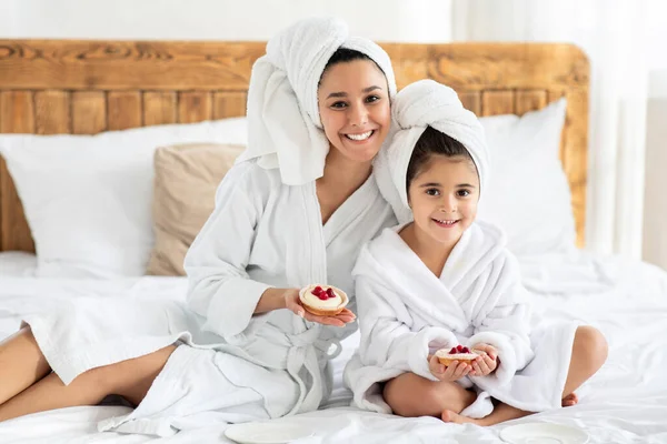 Bella madre e bambino indossando accappatoi, mostrando pasticceria — Foto Stock