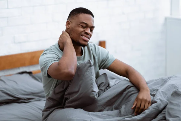 Africano cara sofrendo de dor no pescoço acordar no quarto — Fotografia de Stock