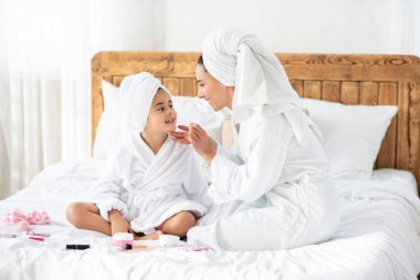 Neşeli anne ve kızı makyajla oynuyorlar.