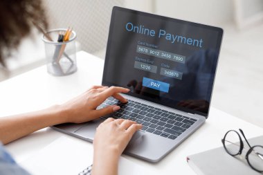 Ödeme formunu dolduran siyahi kadın, ofiste dizüstü bilgisayar kullanıyor.