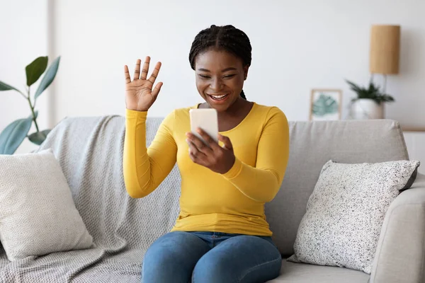 Mutlu genç siyahi bayan evde akıllı telefonuyla video görüşmesi yapıyor. — Stok fotoğraf