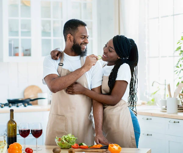 Cônjuges afro-americanos românticos cozinhando almoço delicioso saudável juntos na cozinha — Fotografia de Stock