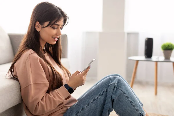 Primer plano de la mujer sonriente usando el teléfono inteligente en casa —  Fotos de Stock