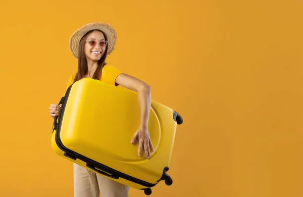Usmívající se mladá žena drží kufr a dívá se na kopírovací prostor — Stock fotografie