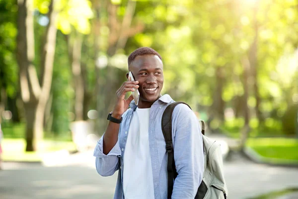 Retrato de homem afro-americano bonito conversando com seu amigo no celular no parque — Fotografia de Stock