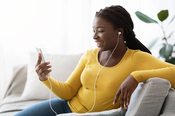 Nero femmina ascolto musica o fare videochiamata su smartphone a casa — Foto Stock