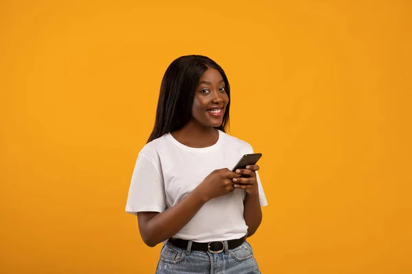 Excitada senhora negra segurando smartphone em sua mão — Fotografia de Stock