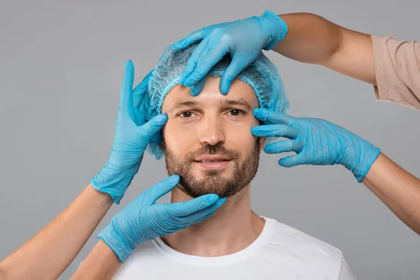 Lekarze w rękawiczkach ochronnych dotykający twarzy człowieka przed operacją — Zdjęcie stockowe