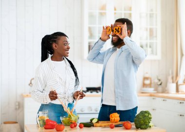 Olumlu genç siyah eşler evde yemek pişirirken eğleniyorlar.