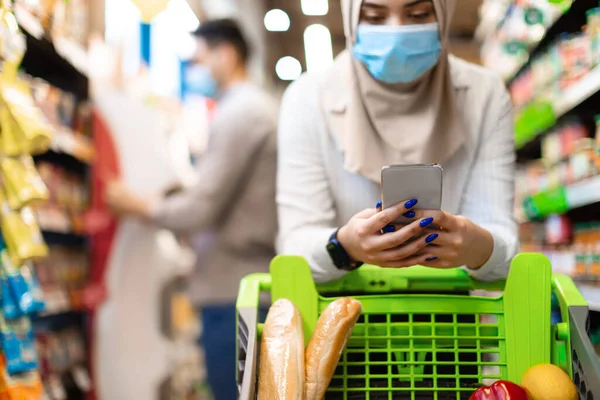 Μουσουλμάνα κυρία κάνει ψώνια παντοπωλείο χρησιμοποιώντας το τηλέφωνο στο σούπερ μάρκετ, περικοπεί — Φωτογραφία Αρχείου