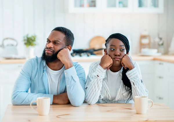 Problemas en la relación. Ofendida pareja negra sentada en la mesa en la cocina — Foto de Stock