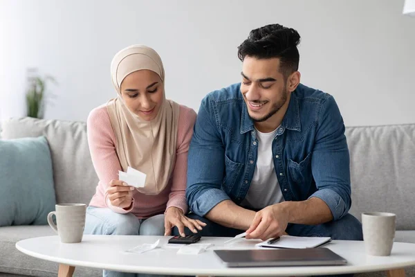 Улыбающиеся мужчина и женщина в хиджабе работают над семейным бюджетом — стоковое фото