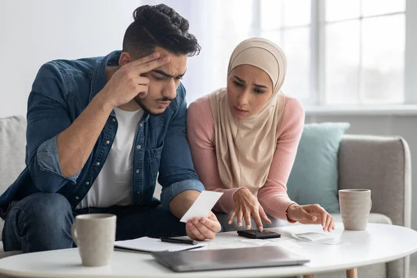 Verwirrte Dame im Hidschab und ihr aufgebrachter Ehemann mit Scheinen — Stockfoto