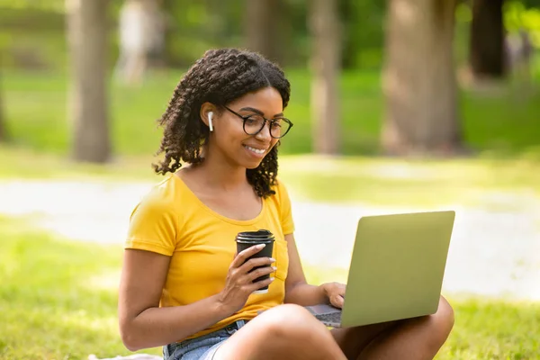 Educación en línea. Estudiante enfocada con café usando laptop en el parque en verano — Foto de Stock