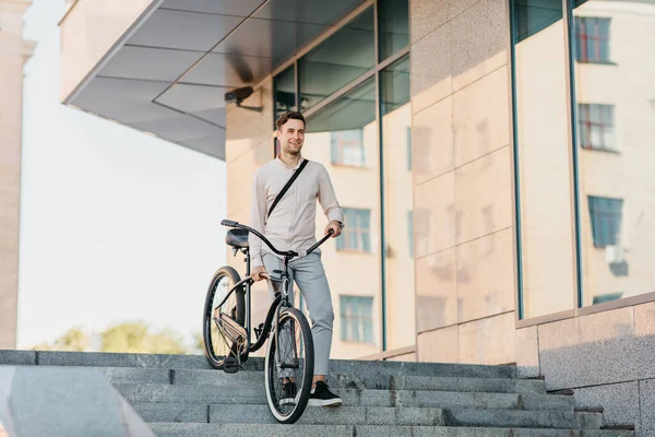 Zelfverzekerde jonge zakenman loopt met eco-vervoer op straat in de stad, gaat werken en een actieve levensstijl — Stockfoto