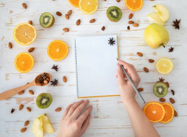 Kadın eli, sağlıklı yemek arka planı, üst görünümü, düz yatış alanı, kopyalama alanı üzerine boş deftere yazar.