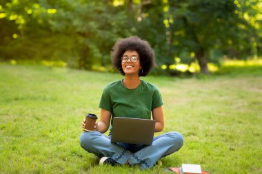 Kampüste dinlen. Afrikalı Öğrenci Kız, dışarıda kahve ve bilgisayarla dinleniyor.