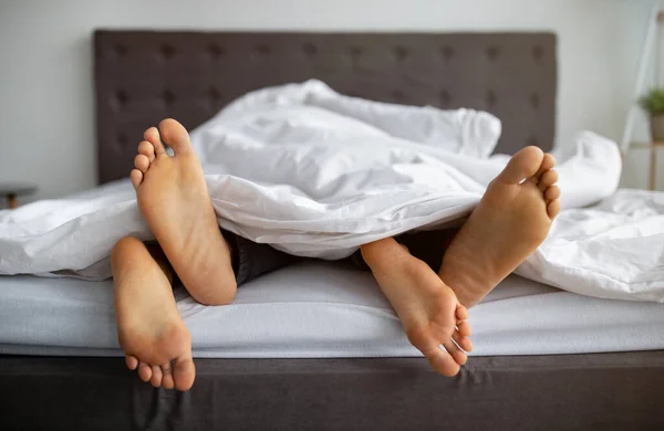 Gepassioneerd interraciaal paar het maken van de liefde, het hebben van seks in bed thuis, close-up van voeten — Stockfoto